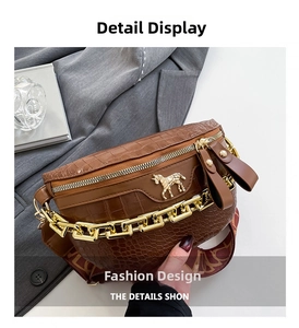 Detail der braunen Krokodilleder-Brusttasche mit Goldkette und pferdeförmiger Metallschnalle