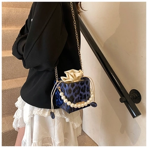 Detail of blue leopard print bucket bag featuring pearl handle and drawstring pouch