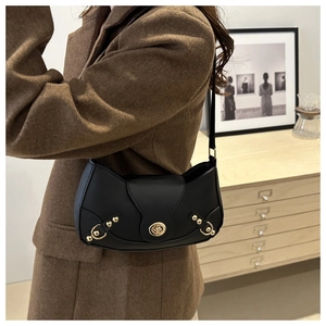 Detail of a black crescent shoulder bag featuring a golden buckle and twist-lock closure