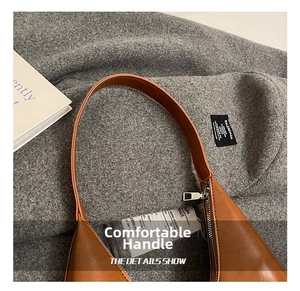 Detailed macro of wide leather strap and silver zipper on caramel brown crescent bag