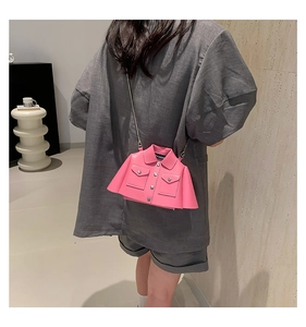 Pink shirt-shaped crossbody bag with silver chain worn by a model in a minimalist setting