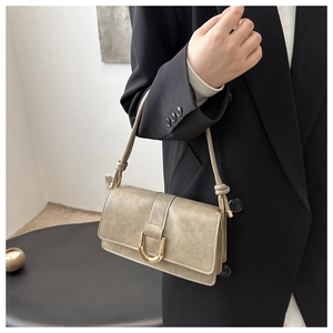 Borsa a spalla verde oliva con fibbia a U dorata indossata da modella in completo nero