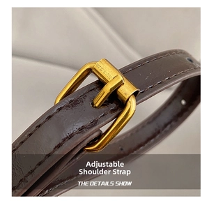 Detail of adjustable brown leather shoulder strap with vintage gold buckle and stitching
