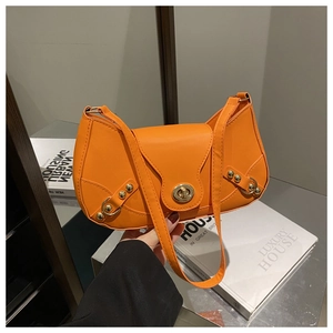 Detail view of orange leather saddle bag with golden metal buckle and decorative rivets