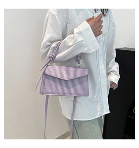 Detail view of lavender woven handbag with knot handle and adjustable crossbody strap