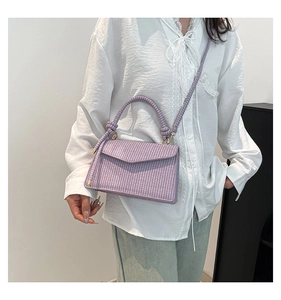 Detailed close-up of a lavender woven crossbody bag held by a model in a casual outfit