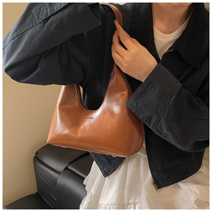 Brown oil-wax leather hobo bag worn by model, showing retro minimalist crescent shape