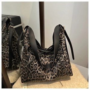 Detail of leopard print tote bag with black leather bow and elegant gold hardware