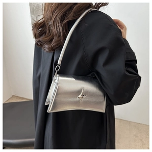 Dettaglio borsa a tracolla argento metallizzato con decoro a stella su camicia nera