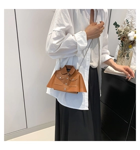 Detailed view of caramel jacket-shaped crossbody bag with silver chain strap on model