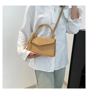 Detail of hand-woven straw crossbody bag with decorative knot handle and paper rope texture