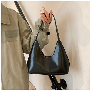 Detail of a black glossy leather crescent hobo bag with subtle brand embossing