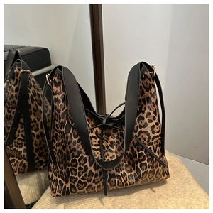 Close-up of leopard print tote bag with black faux leather straps and gold buckle detail