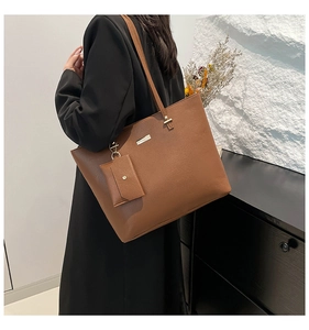 Detail of caramel brown pebbled leather tote bag with metallic logo and detachable mini pouch