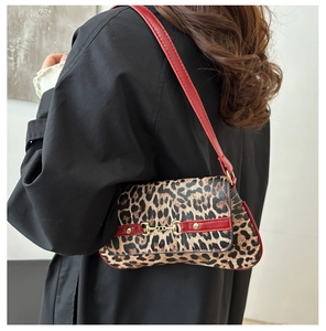 Detail view of leopard print shoulder bag with red strap on black coat backdrop