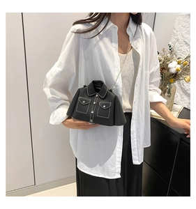 Detail of jacket-shaped black leather crossbody bag with white stitching and metal chain