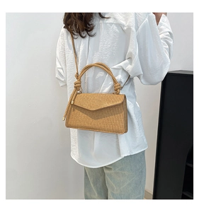 Detail of straw woven crossbody bag with top handle and fine textured material