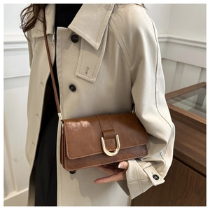 Primo piano di una borsa a tracolla marrone vintage con fibbia in metallo dorato a U