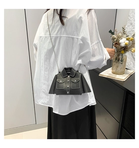 Detail of creative shirt-shaped crossbody bag with white stitching and metal chain strap