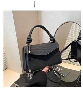 Detail of black woven texture leather bag with unique knot handle and gold hardware buckle