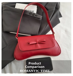 Detail of red baguette bag with bow decoration on grey suit and white book background