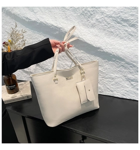 Close-up of white lychee pattern tote bag with matching envelope pouch and gold metal logo