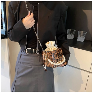 Detail of leopard print bucket bag with pearl handle and golden chain on model