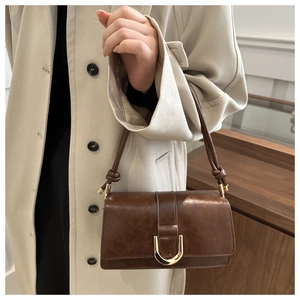 Dettaglio borsa vintage marrone scuro in ecopelle con fibbia a U dorata e tracolla