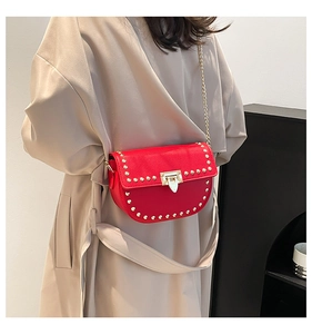 Chic red semi-circular crossbody bag with golden rivets shown on a beige coat outfit