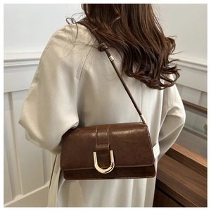 Dettaglio di una borsa a tracolla marrone scuro vintage con fibbia in metallo a U