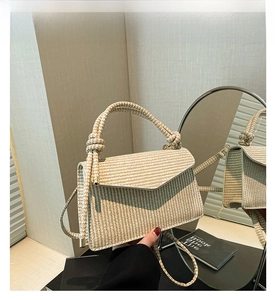 Detail of khaki woven crossbody bag showing textured houndstooth pattern and knot handle