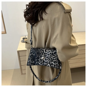Dettaglio borsa a tracolla leopardata con fibbia a stella argento indossata con trench