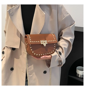 Detail of dark brown saddle bag with gold stud trim and textured lychee leather