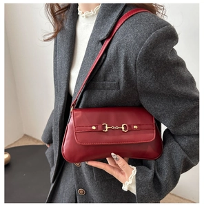 Close-up of burgundy leather shoulder bag with golden horsebit buckle and stud details