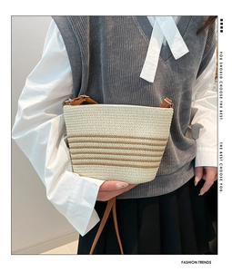 Detail of hand-woven tote bag featuring beige and brown stripes with a brown leather strap