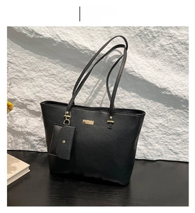 Detail of black pebbled leather tote bag with gold nameplate and matching small pouch