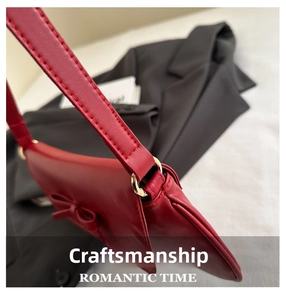Detail of red leather shoulder bag showing bow knot and gold metal ring hardware