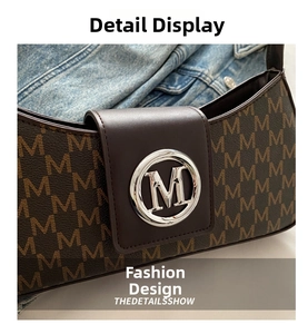 Detail of vintage brown underarm bag with M-letter print and silver logo on denim