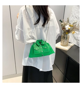 Close-up of a grass green jacket-shaped crossbody bag with metal chain and lapel detail