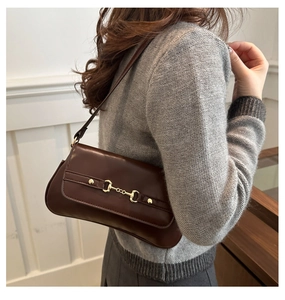 Close-up of dark brown leather baguette bag with vintage gold horsebit hardware detail