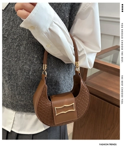 Dettaglio di una borsa a mano marrone a mezzaluna con texture intrecciata e fibbia d'oro