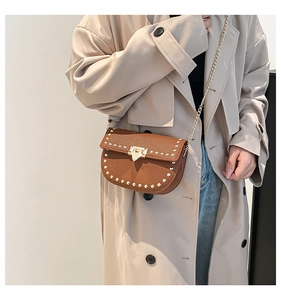 Detail of caramel lychee leather saddle bag featuring gold rivets and heart-shaped lock