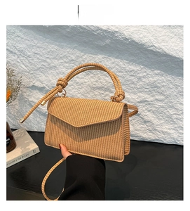 Detail view of woven straw shoulder bag in light brown with textured flip-top design