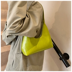 Side view of lime green crescent shoulder bag on model in modern indoor staircase setting