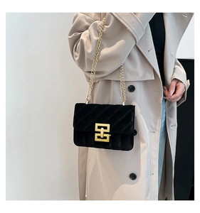 Détail du sac bandoulière matelassé en velours avec chaîne dorée et fermoir métallique chic