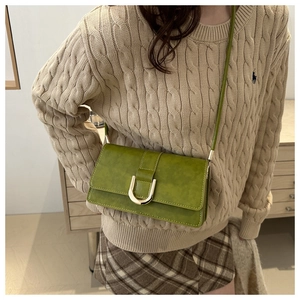 Dettaglio borsa a tracolla verde avocado con fibbia a U dorata su maglia intrecciata
