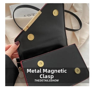 Detail of black saddle bag with golden magnetic buckles and red edge oil finish