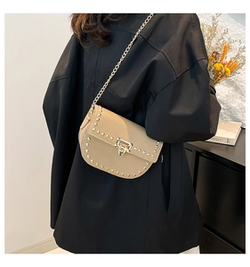 Détail d'un sac bandoulière kaki en cuir grainé avec rivets dorés et bandoulière