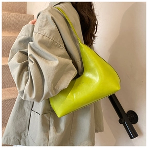 Lime green crescent shoulder bag worn by model, showing smooth leather texture and side view