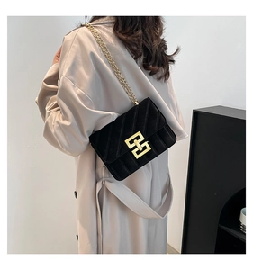 Détail d'un sac bandoulière en velours noir avec motif matelassé et fermoir doré en H